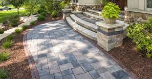 Paver walkway with stone pillars and steps leading to a home