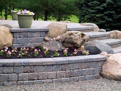 Block retaining wall with boulders and planting bed